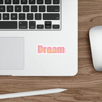 Sticker with 'Dream Bigger' text in pink and orange on a white background