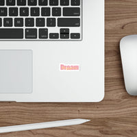 Sticker with 'Dream Bigger' text in pink and orange on a white background