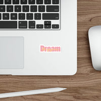 Sticker with 'Dream Bigger' text in pink and orange on a white background